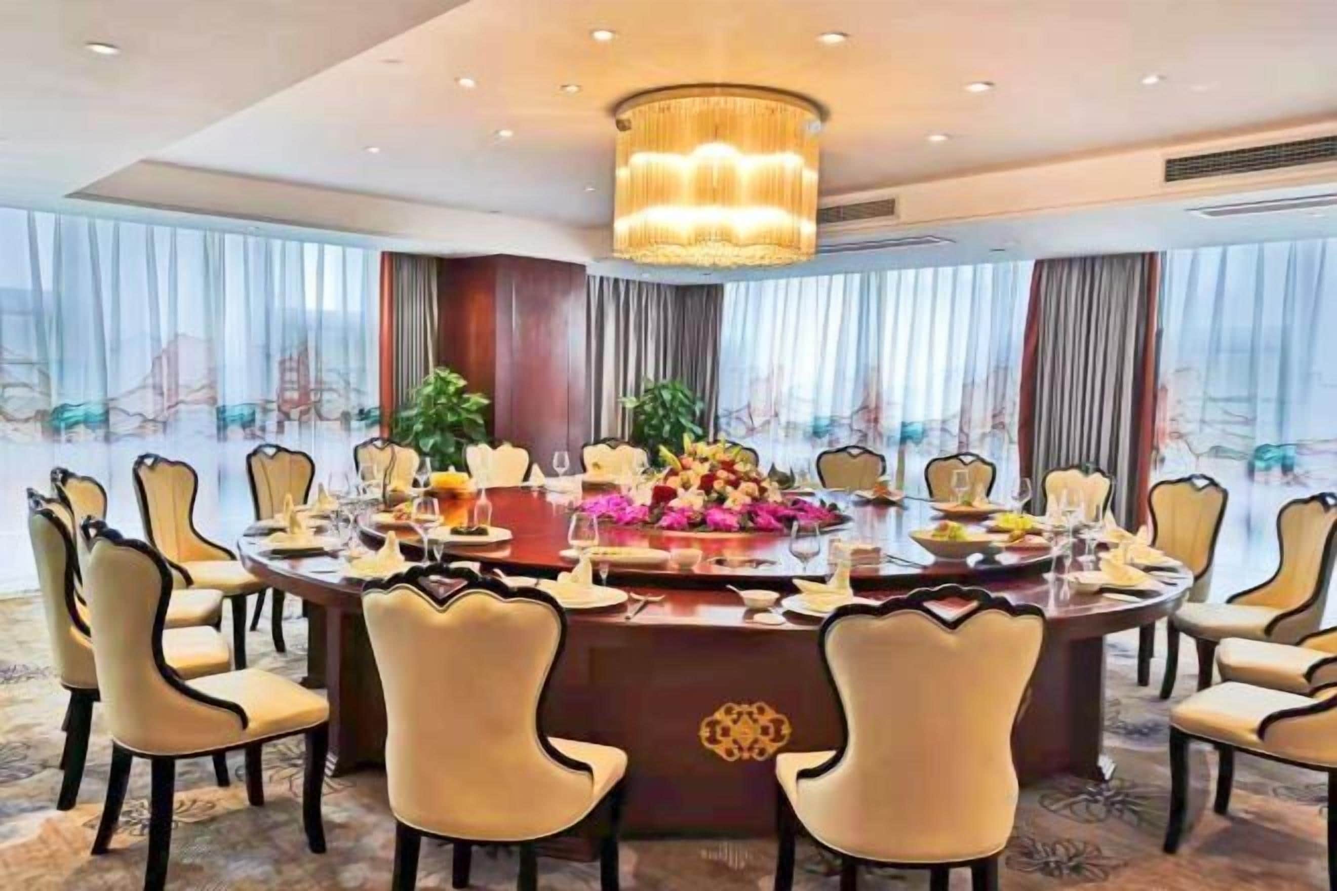 A conference room with a round table, chairs, and a chandelier.