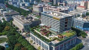 An urban building complex with multiple high-rise structures, a central courtyard with greenery, and a mix of modern and traditional architectural styles. - Century Chanson Hotel (Mianyang)