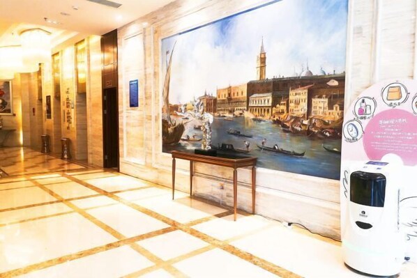 A hotel lobby with a large painting of a canal scene, a marble floor, and a table with a small statue. - Century Chanson Hotel (Mianyang)