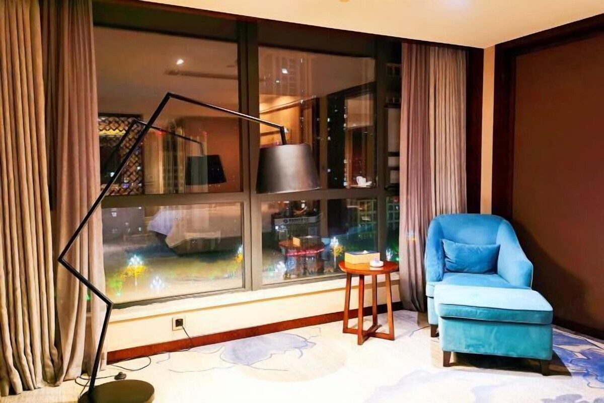 A modern living room with a large window, a blue armchair, and a floor lamp.