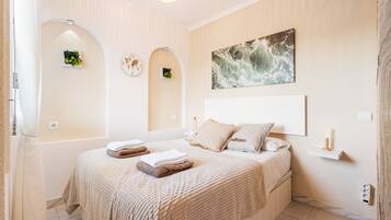 A bedroom with a large bed, a wall clock, a painting, and a small shelf.