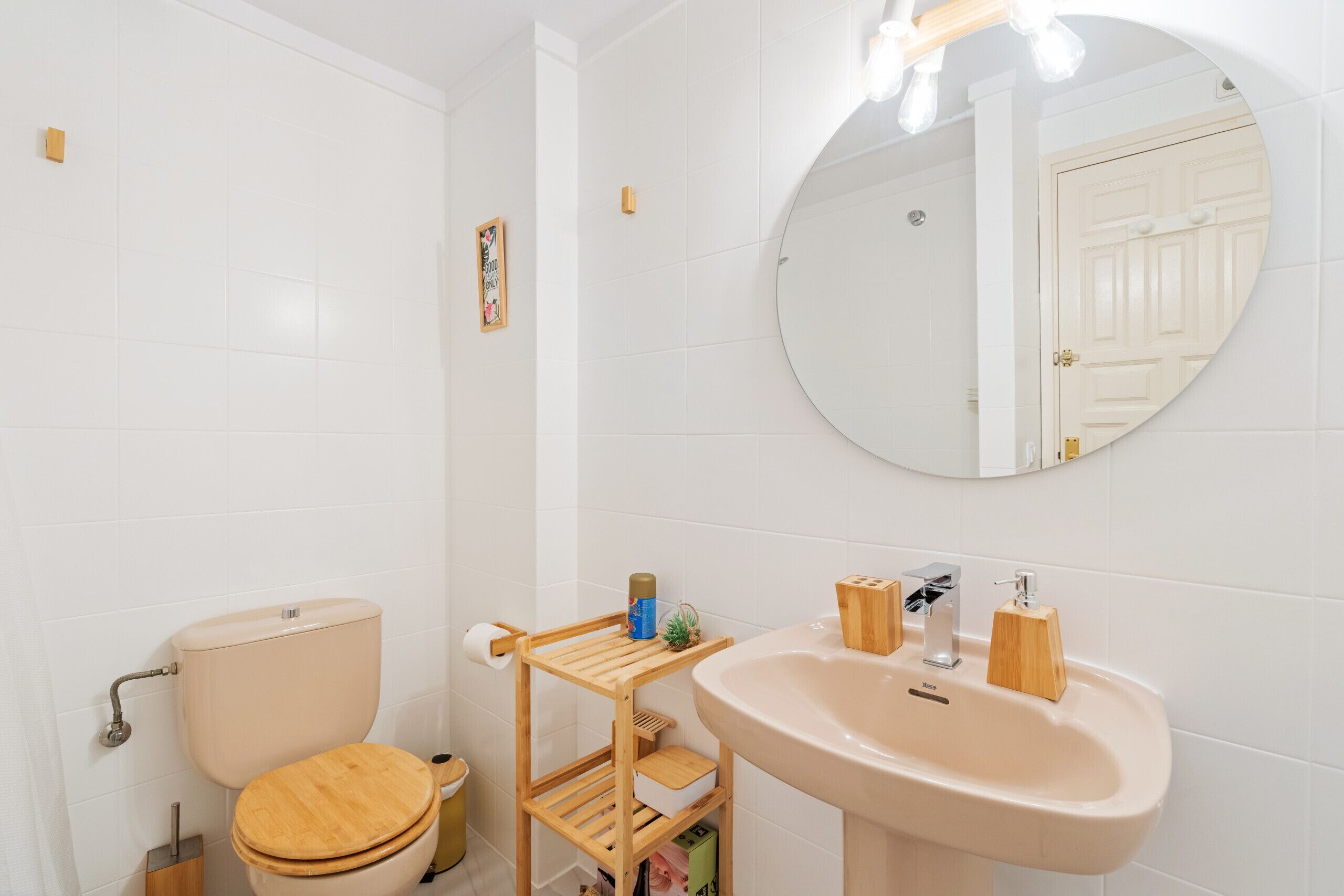 A bathroom with a toilet, sink, and mirror.