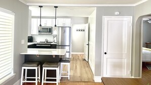 A modern kitchen with white cabinetry, a stainless steel refrigerator, and a central island with stools. - Modern Comfort in Downtown Greenville 4br 2ba (Greenville)