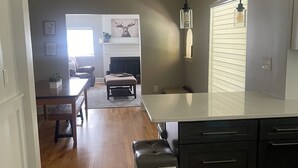 A modern kitchen with a large island, wooden flooring, and a dining area with a fireplace. - Modern Comfort in Downtown Greenville 4br 2ba (Greenville)
