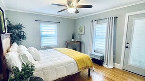 A bedroom with a bed, a ceiling fan, a window, and a door. - Modern Comfort in Downtown Greenville 4br 2ba (Greenville)