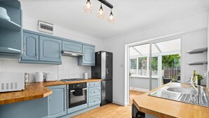 A modern kitchen with light blue cabinets, a black refrigerator, and a wooden countertop. - The unit comes high-speed WiFi, hotel-quality linen, and toiletries for your comfort. (Birmingham)