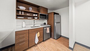 A modern kitchen with wooden cabinets, a stainless steel refrigerator, a microwave, and a dishwasher. - MainStay Suites Foxboro – Mansfield (Foxborough)