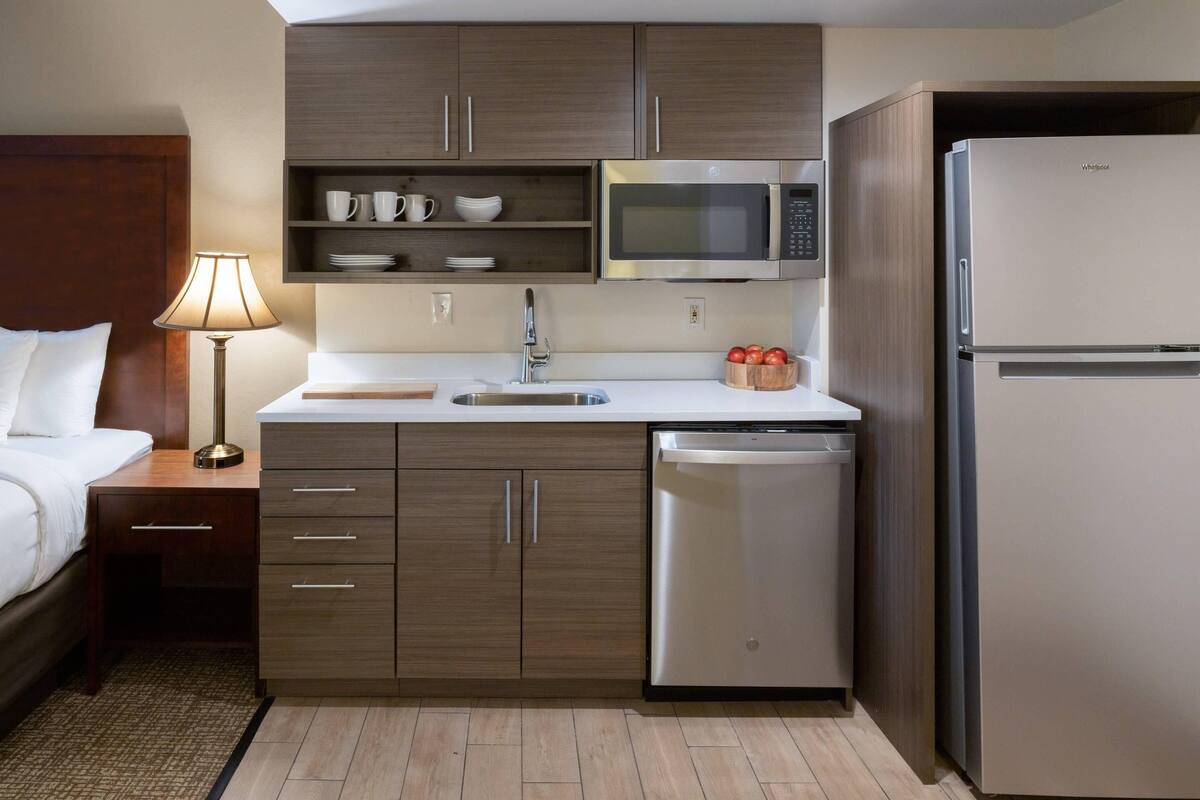 A compact hotel room with a kitchenette, including a microwave, refrigerator, and dishwasher.