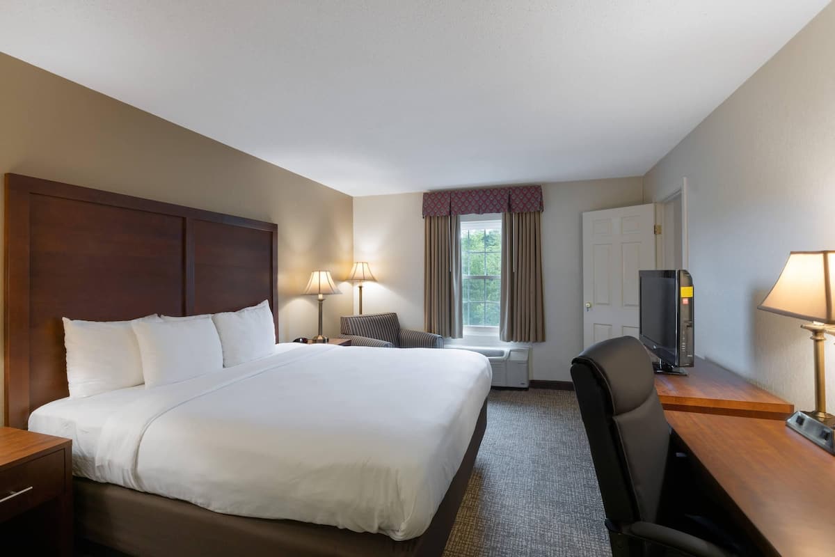 A hotel room with a large bed, a desk with a computer, a chair, and a television.
