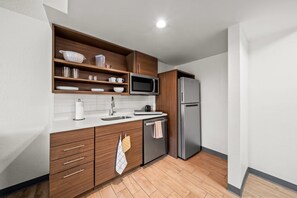 Uma cozinha moderna com armários de madeira, geladeira de aço inoxidável, micro-ondas e lava-louças.