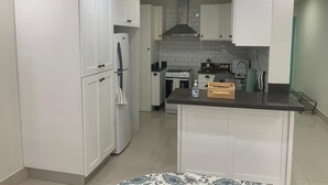 A modern kitchen with white cabinetry, a central island, and a stainless steel range hood. - Punta Cana 2BR apt with private jacuzzi (Punta Cana)