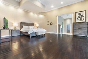 A spacious bedroom with a large bed, bedside tables, a dresser, and a walk-in closet. - Uncommon Grounds Estate (Dallas)