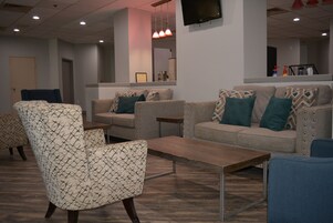 Un vestíbulo moderno con un sofá, un sillón y una pequeña mesa.