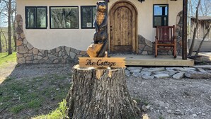 Une cabane rustique avec une façade en pierre, une porte en bois et un banc à l’extérieur.