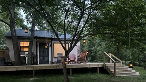 Un chalet rustique doté d’une terrasse en bois, d’un mur en pierre et d’un escalier menant à l’entrée.