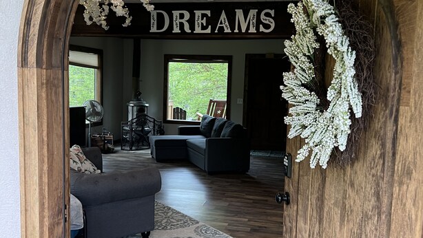 Un intérieur avec une arche en bois, une enseigne sur laquelle on peut lire «RÊVES», et un salon avec un canapé et un tapis.