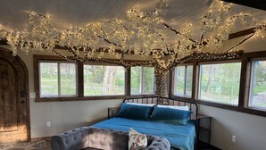 Une chambre avec un grand lit, un canapé et une décoration en forme d’arbre suspendue au plafond.