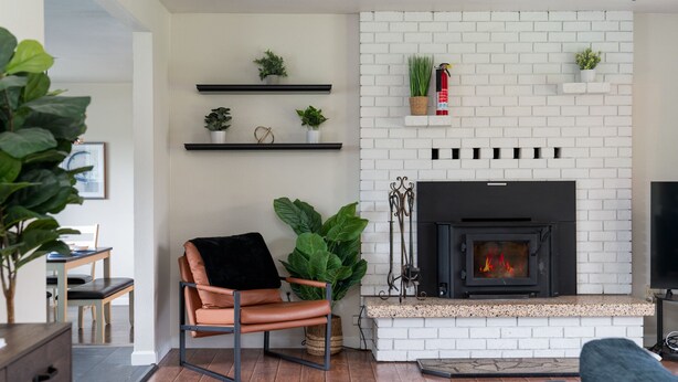A living room with a fireplace, a sofa, a chair, and potted plants.