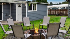 A backyard with a fire pit surrounded by four chairs.