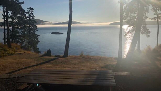 Un banc en bois donnant sur un lac paisible, sous un ciel dégagé.