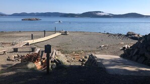 Une plage avec une jetée en bois, un petit bateau et une côte rocheuse.
