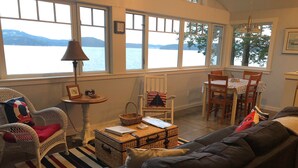 Un salon chaleureux avec vue sur un lac, des meubles en osier et un tapis à rayures.