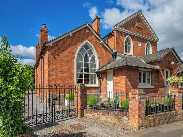 A red brick building with a large arched window and a white door.