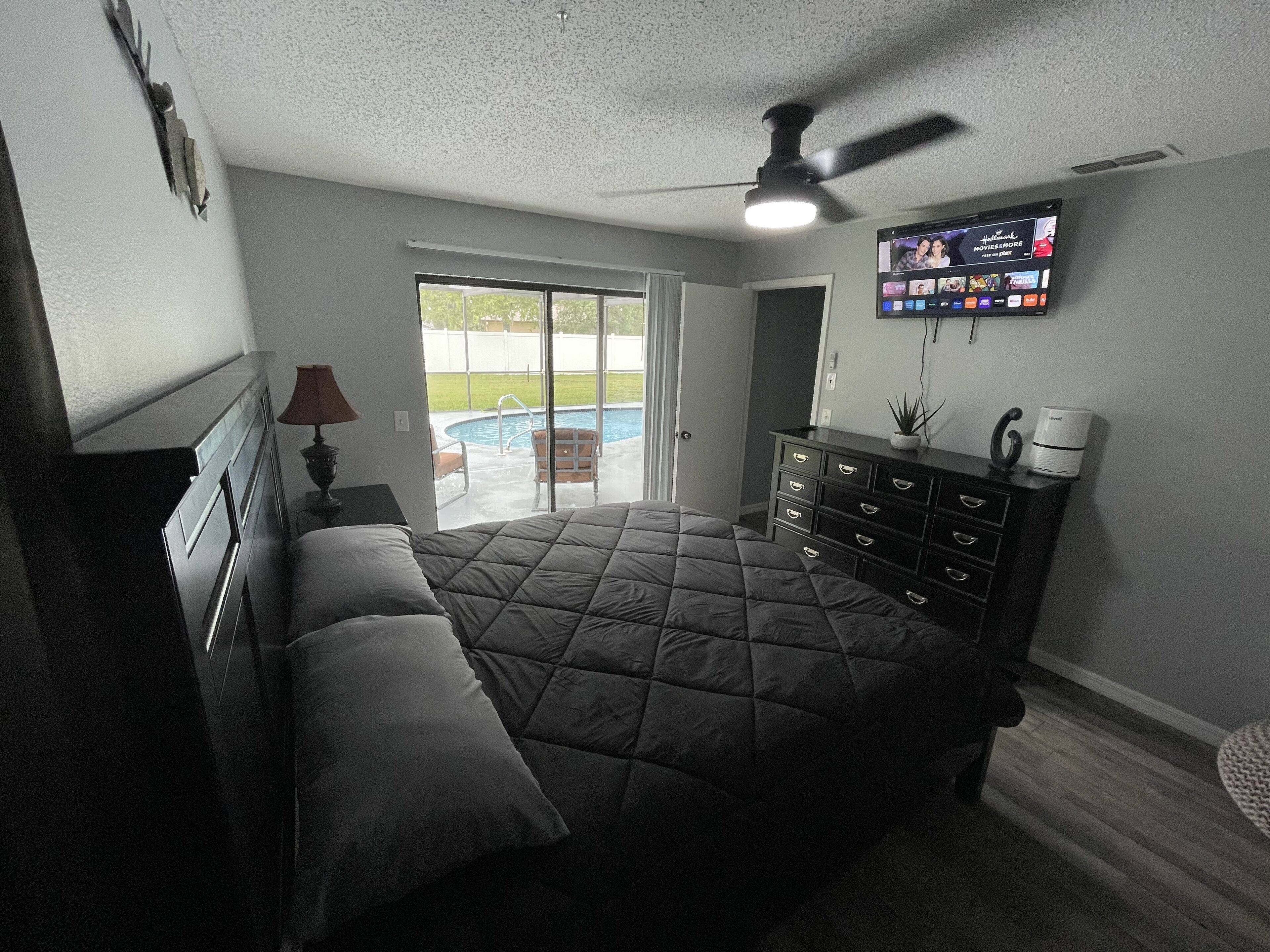 Un dormitorio con cama, cómoda y televisor fijado a la pared.