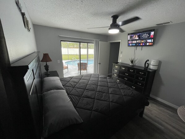 A bedroom with a bed, dresser, and a TV mounted on the wall.