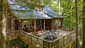 Une cabane en rondins avec un porche, un espace salon extérieur et une terrasse.