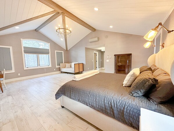 A spacious bedroom with a large bed, a built-in wardrobe, and a chandelier.