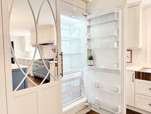 A modern kitchen with white cabinetry, a built-in oven, and a wine fridge.