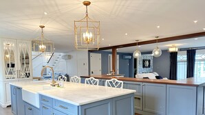 A modern kitchen with a large island, white cabinetry, and pendant lighting. - Spacious Home Near Wallis Sands Beach in Rye NH (Rye)