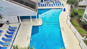 Una piscina con poltrone da relax blu, una zona coperta con tetto e un pannello solare sul tetto.