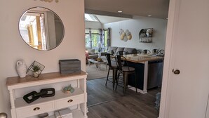 Un interno moderno con zona pranzo, cucina e un tavolino consolle bianco con oggetti decorativi.