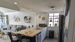 Una cucina moderna con isola in legno, sgabelli da bar e forno a microonde integrato.