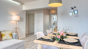 A dining area with a table set for four, white chairs, and a modern pendant light.