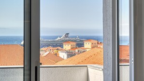 A view of a cruise ship from a window overlooking a coastal town with red-roofed buildings.