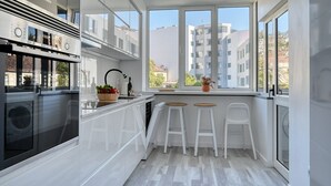 A modern kitchen with white cabinets, a Bosch oven, and a window with a view of buildings.