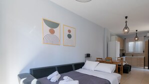 Une chambre d’hôtel moderne équipée d’un grand lit, d’un bureau et d’une kitchenette.