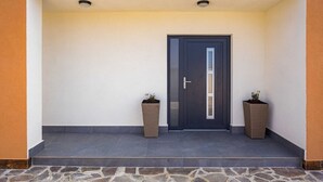 A modern entrance with a dark door, two potted plants, and a stone-tiled floor. - Villa Nur Amela - Pool, Jacuzzi, Darts (Pula)