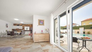 A spacious living area with a dining set, a kitchen, and a sliding glass door leading to a pool. - Villa Nur Amela - Pool, Jacuzzi, Darts (Pula)