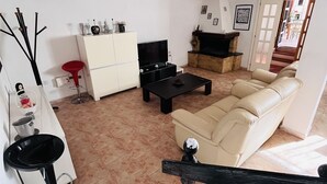 Ein modernes Wohnzimmer mit Sofa, Fernseher und Kamin.