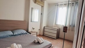 Ein modernes Schlafzimmer mit einem großen Bett, einem Nachttisch, einem Spiegel und einem Kleiderschrank.