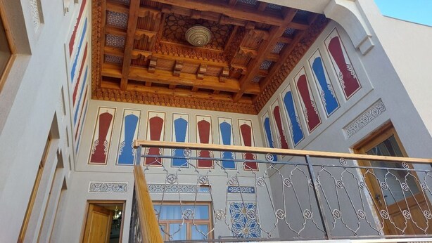 A building with a wooden ceiling and decorative blue and red patterns on the walls. - Nostalgia boutique hotel (Bukhara)