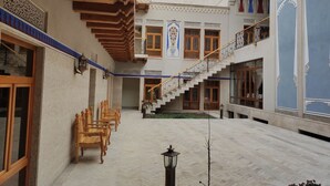 A courtyard with wooden benches, a staircase, and a decorative wall. - Nostalgia boutique hotel (Bukhara)