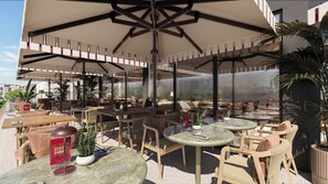 An outdoor seating area with round tables and chairs, covered by large umbrellas, and surrounded by potted plants. - Holiday Inn & Suites Kocaeli - Dilovasi Gulf View by IHG (Dilovasi)