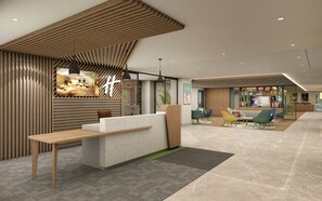 Un área de recepción moderna con un mostrador de madera, zona de estar con sillas coloridas y una pantalla grande mostrando contenido.