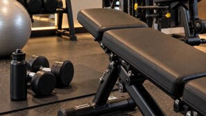 A gym with exercise equipment, a bench, dumbbells, and a yoga ball.