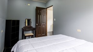 Een slaapkamer met een bed, een ladekast, een spiegel en een deur.